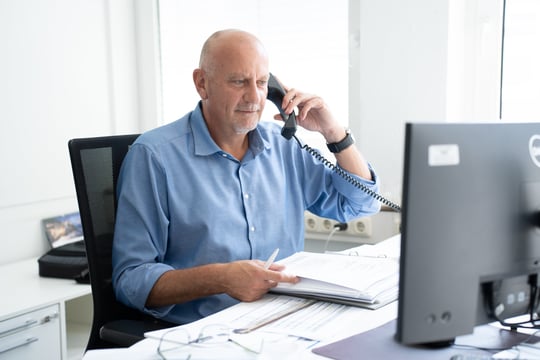 Frank Nagel sits at his desk and holds a telephone to his ear