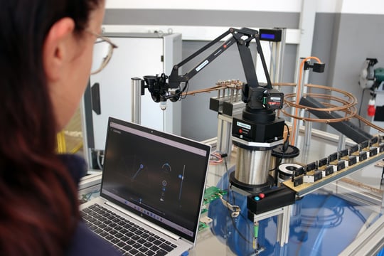 Auszubildende Maschinen- und Anlagenführerin bedient eine Maschine mit dem Laptop